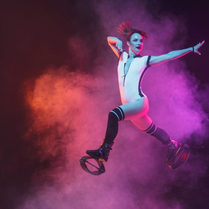 beautiful-redhead-woman-red-sportswear-jumping-kangoo-jumps-shoes-dark-studio-background-scaled.jpg