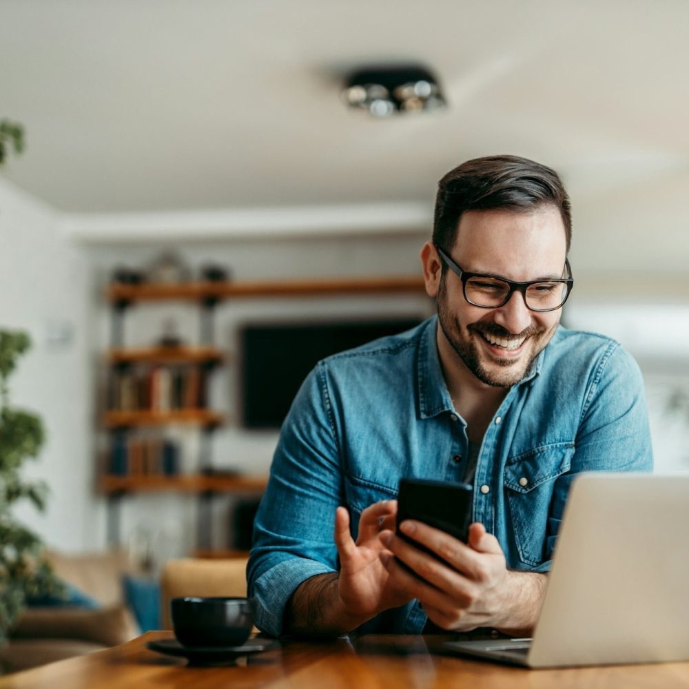 portrait-of-a-happy-man-with-smart-phone-and-laptop-indoors-.jpg