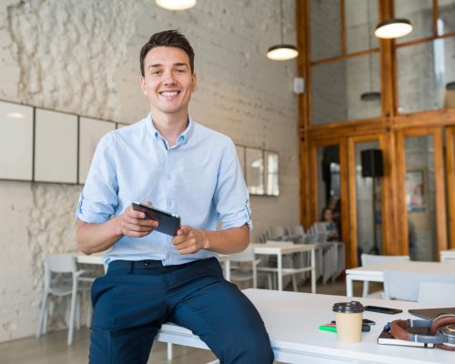 young-stylish-smiling-man-co-working-office-startup-freelancer-holding-using-tablet-scaled.jpg